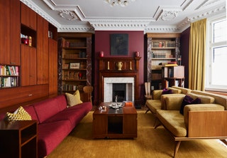 Mustard and burgundy hues create a cozy yet bold atmosphere in the library where the initial piece was a large 1960s Joe...