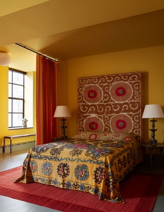 Guest suite with yellow walls red rug and curtain yellow patterned bed with upholstered headboard two side tables