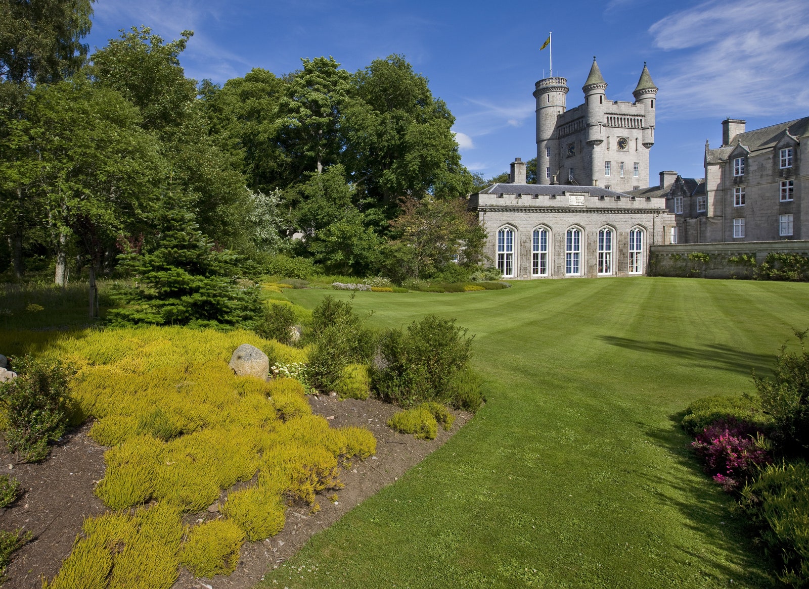 The mowed grass lawn and landscaped shrubbery at Balmoral castle in far background